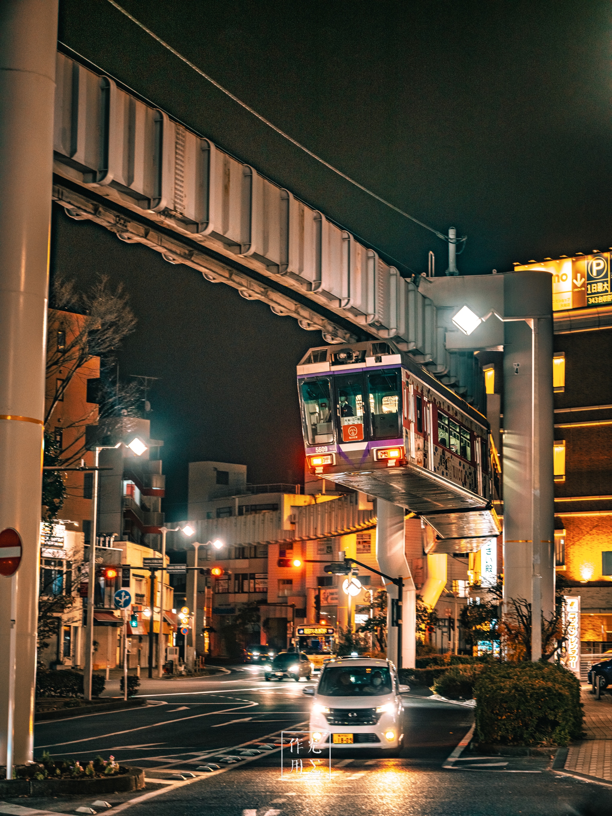 suspended tram, elevated track, car, streetlamp, illuminated storefronts