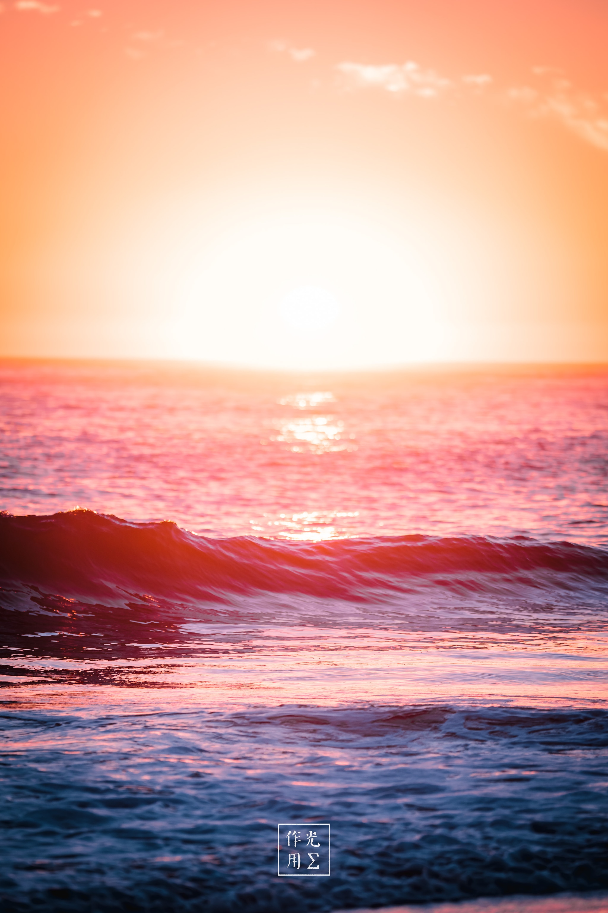 Drenching the horizon in molten rose and tangerine, the sun hovers at the water’s edge like a burning gem. Rippling breakers catch its fiery glow, each crest outlined in shimmering gold before dissolving into violet-tinted foam. Delicate wisps of cloud scatter above, softening the blaze into a gentle gradient that promises warmth long after dusk. The restless motion of the sea contrasts the sky’s hushed brilliance, creating a moment both electric and serenely infinite