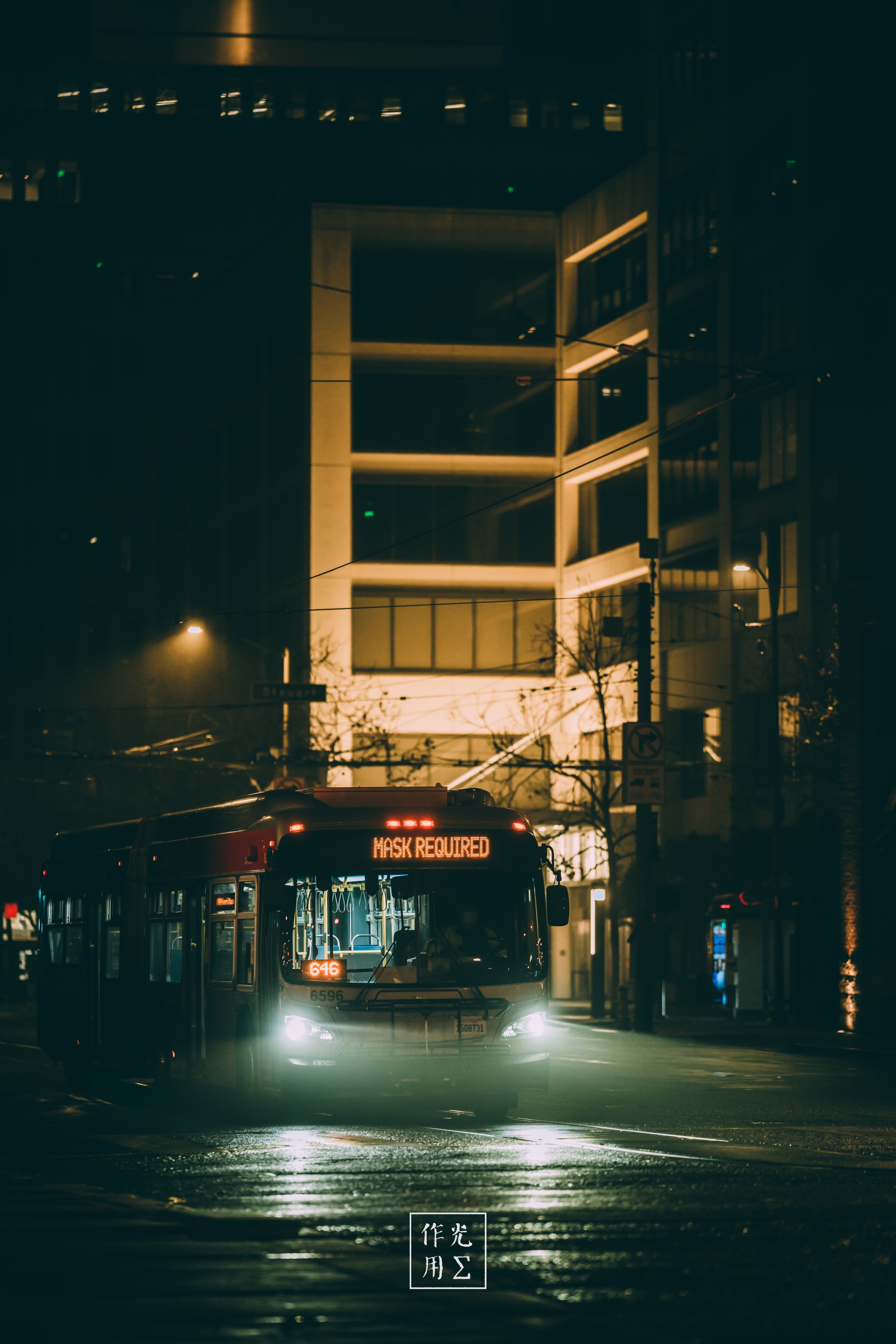 bus, illuminated building facade, wet pavement reflections, streetlight, storefront signage